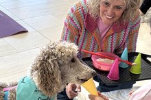 Karin Bäder kniet neben ihrem Besuchshund, Großpudel Emely, im Seniorenzentrum Mosbach